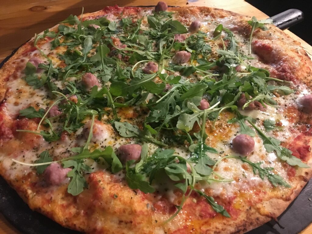 Pizza de mascarpone, tomate seco, bocconcini, salchicha y rúcula